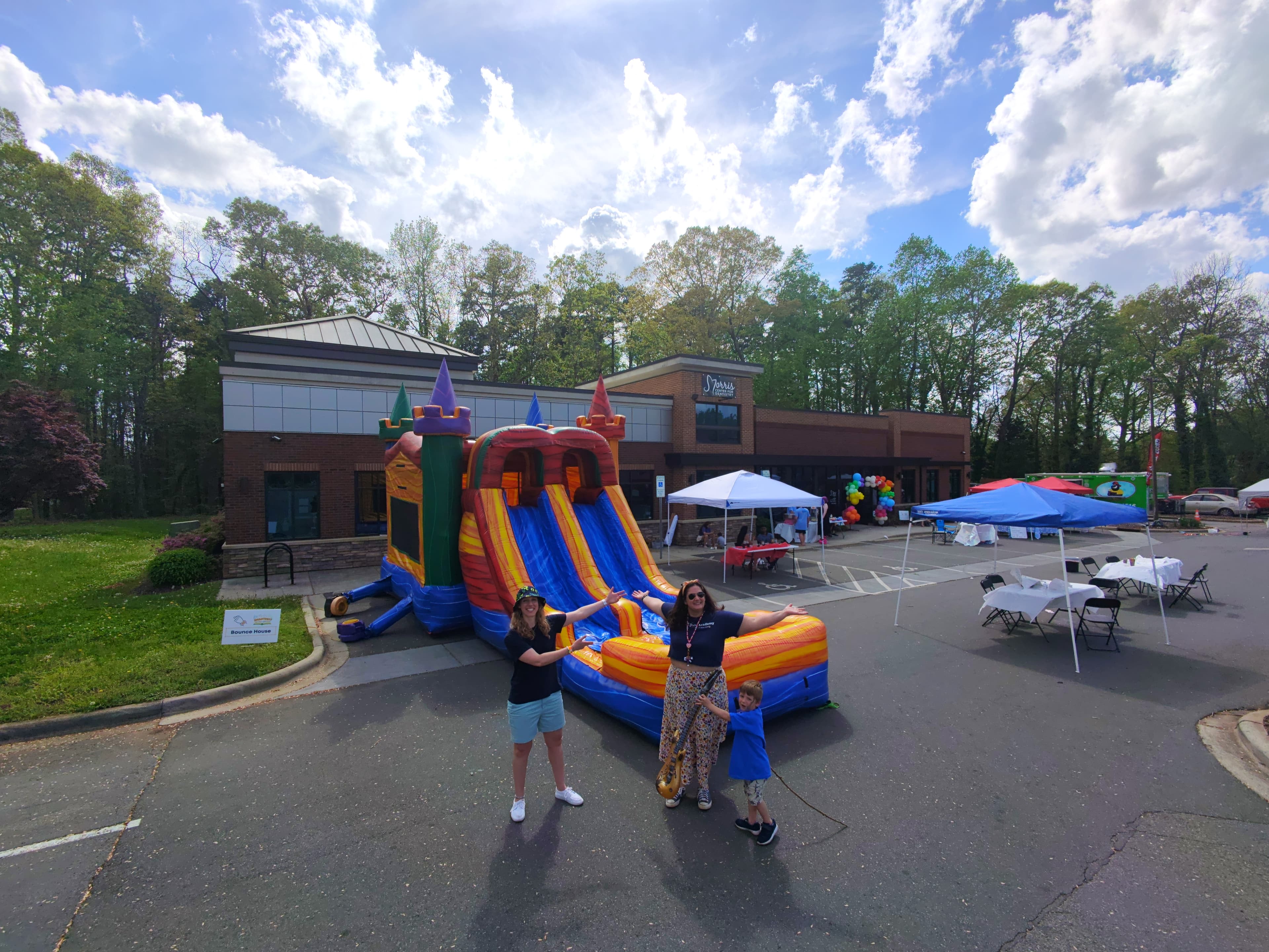 Two people posing in front of the large colorful bounce house and slide combo at SmartFest