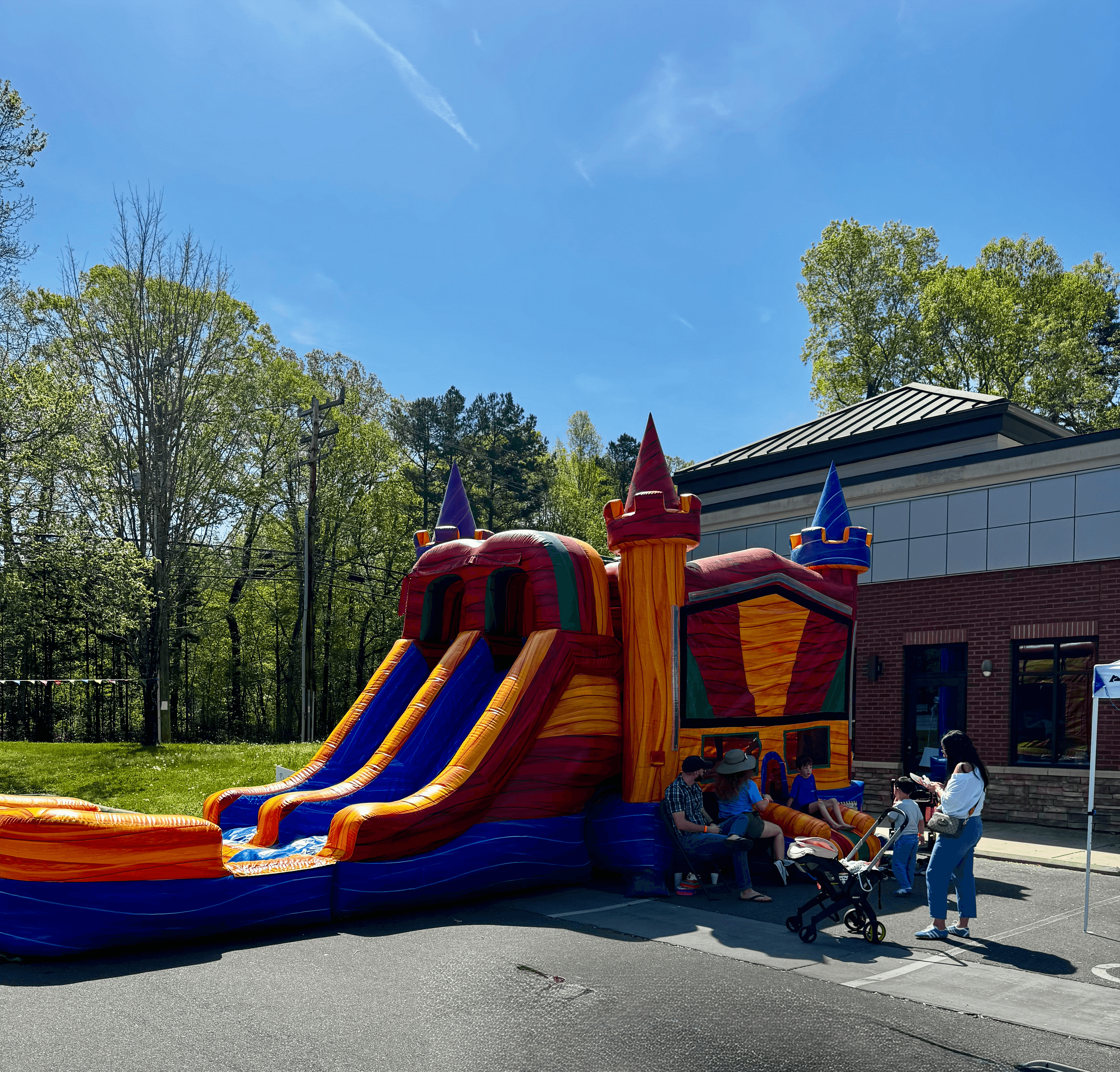 Families gathered around the bounce house with blue sky in the background at SmartFest